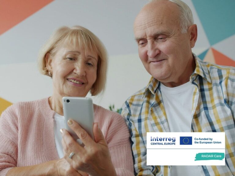 Két hatvanas éveiben járó nő és férfi egy mobiltelefon képernyőjét nézi.